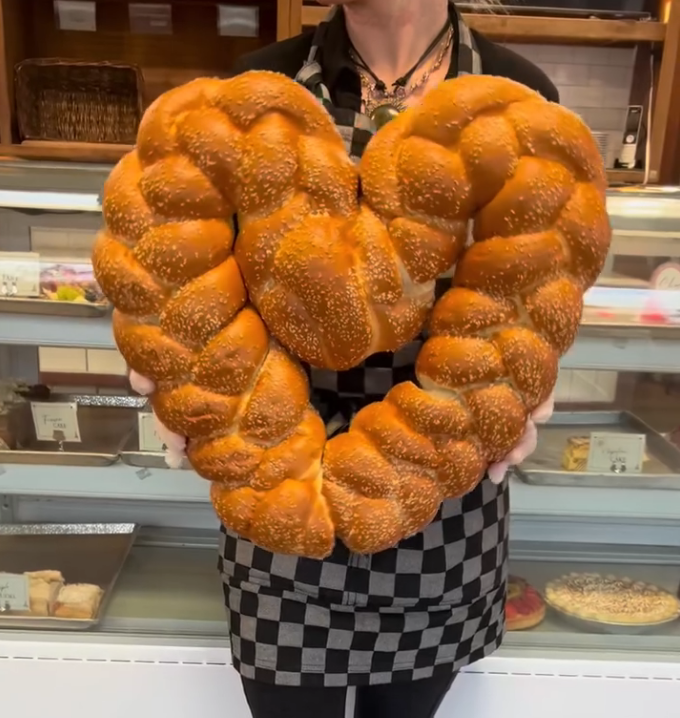 A baker holding a giant braided sesame loaf at Paris Bakery